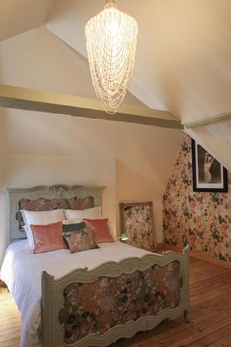 a bedroom with a bed and a chandelier at Le manoir des chevaux dorés in Le Neubourg