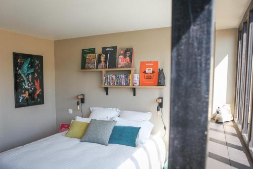 a bedroom with a bed and bookshelves on the wall at Le manoir des chevaux dorés in Le Neubourg