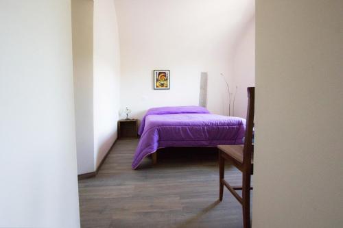 a bedroom with a purple bed in a white room at Agripodere Il Falco in Pontremoli