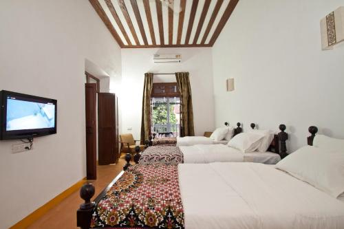 a bedroom with two beds and a flat screen tv at Hospedaria Abrigo De Botelho in Panaji