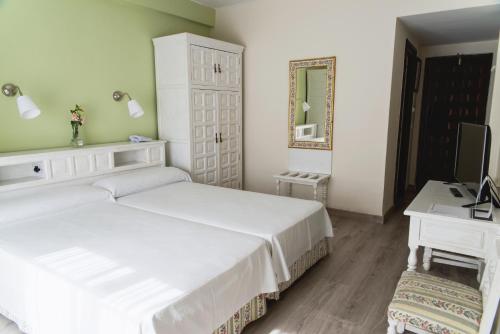 a bedroom with two beds and a desk and a television at TRH Mijas in Mijas