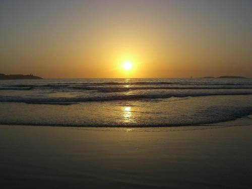 a sunset on a beach with the ocean at Hotel A Queimada in Nigrán