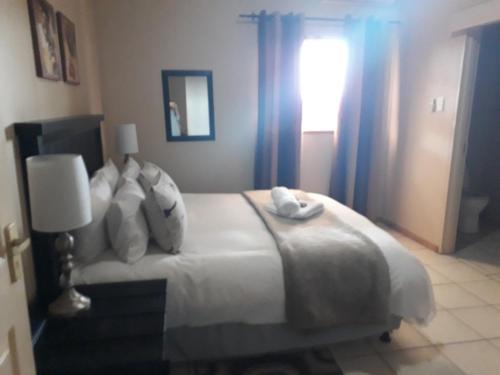 a bedroom with a large white bed with a window at Augrabies De Oude Stoor Guesthouse in Augrabies