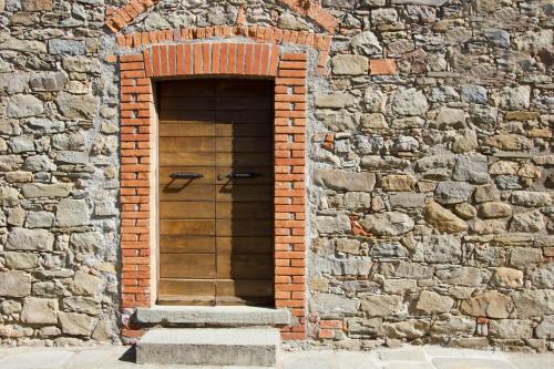 a brick wall with a wooden door in it at Agripodere Il Falco in Pontremoli
