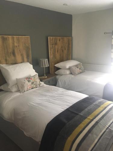 a bedroom with two beds with pillows and a lamp at Hunters Lodge Inn in Totnes