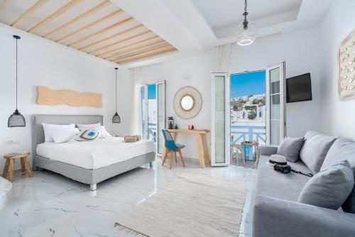 a white bedroom with a bed and a couch at Central Suites Mykonos in Mikonos