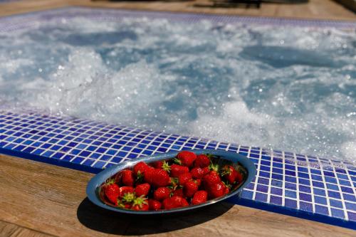 a bowl of strawberries sitting next to a swimming pool at Apartments Petra Krk in Krk