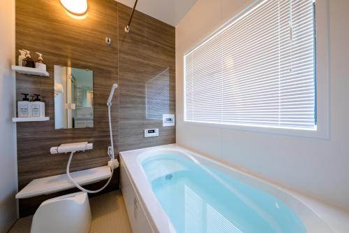 a bathroom with a large tub and a window at Villa Hanasaku Fujikawaguchiko B in Fujikawaguchiko