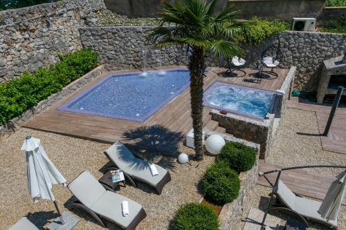 an overhead view of a pool with chairs and a palm tree at Apartments Petra Krk in Krk