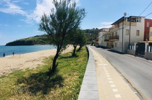 a road next to a beach with trees and buildings at Noemi Holiday House in Agnone Bagni