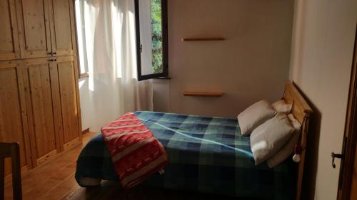ein Schlafzimmer mit einem Bett mit einer karierten Decke und einem Fenster in der Unterkunft I Tre Ciliegi Apartment in SantʼOmobono Imagna