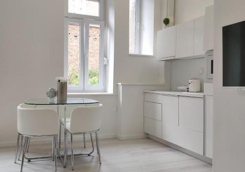 a white kitchen with a table and white cabinets at Luxurios and historic apartment "Shine" - right on the Main Square in Zagreb