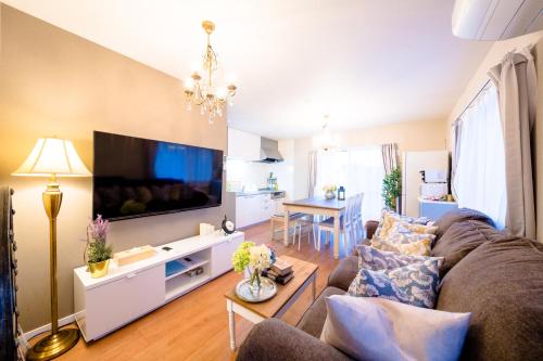 Una sala de estar con un sofá y un televisor de pantalla plana. en villa hanasaku 富士河口湖町A棟, en Fujikawaguchiko