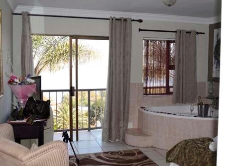 a living room with a tub and a large window at La Dolce Vita Guest House in Hartbeespoort
