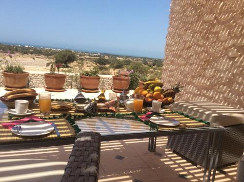 a table with food and drinks on a patio at Villa Sarah in Sidi Kouaki