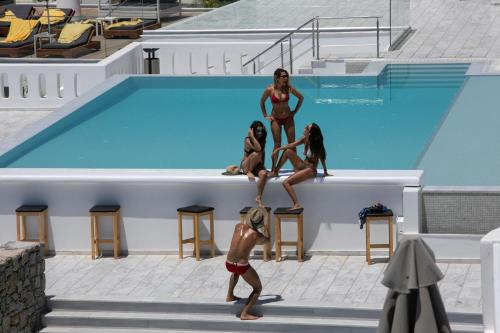 a group of women standing on the side of a swimming pool at The George Hotel Mykonos in Platis Yialos Mykonos