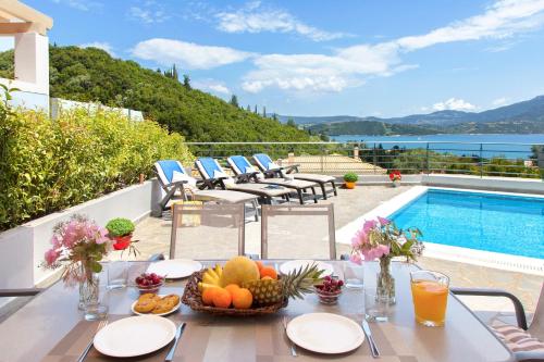 a table with fruit on it next to a swimming pool at Thealos Village in Lygia