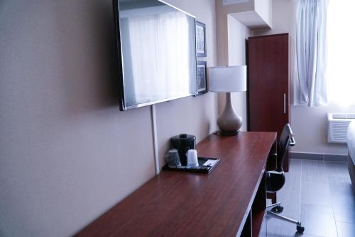 a hotel room with a desk with a television on it at Hotel Mint JFK Airport in Queens