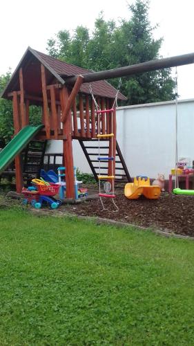 a playground with a wooden play structure in a yard at Aliz Apartman in Nyíregyháza