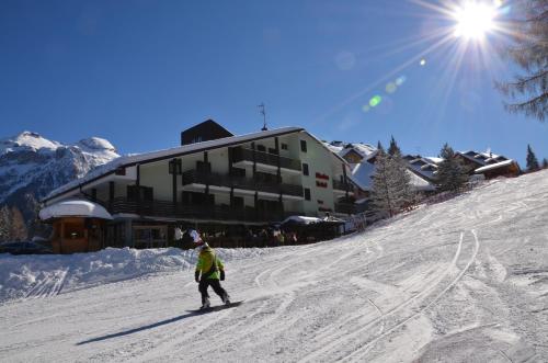a person riding a snowboard down a snow covered slope at Hotel Alaska in Folgarida
