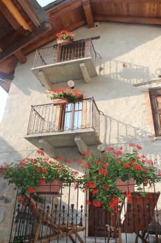 a building with two balconies with red flowers on it at La Maison Des Vignerons Chambres D'Hotes B&B in Donnas