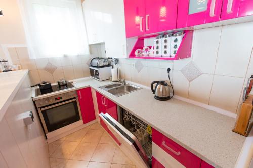 a small kitchen with pink cabinets and a sink at Apartment Green House in Petrovac na Moru
