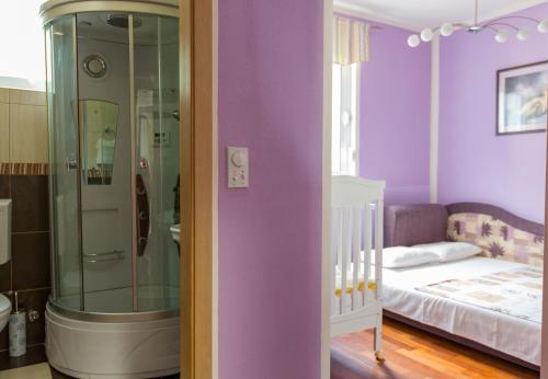 a bedroom with purple walls and a shower and a bed at Apartment Green House in Petrovac na Moru