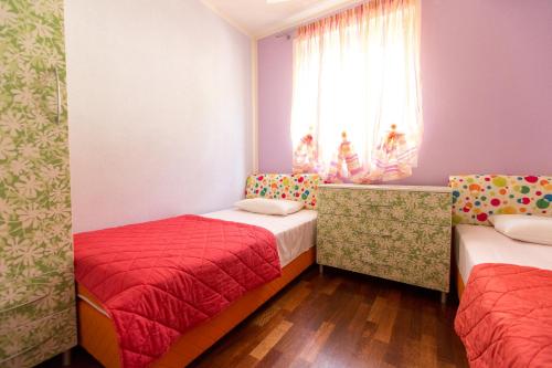 a small room with two beds and a window at Apartment Green House in Petrovac na Moru