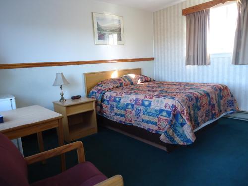 a hotel room with a bed and a chair at Kingsway Inn in Thunder Bay