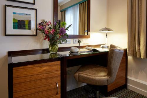 a desk with a vase of flowers and a chair at The Bull in Gerrards Cross