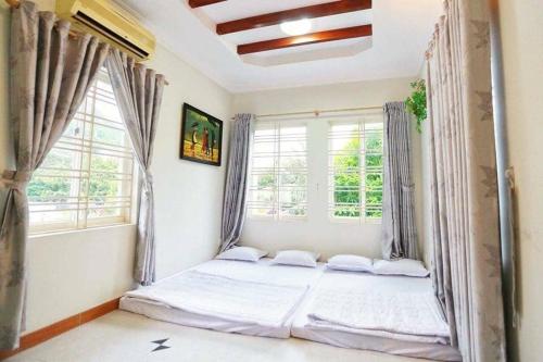 a bed in a room with two windows at Sea Villa - 22 Bà Triệu in Vung Tau