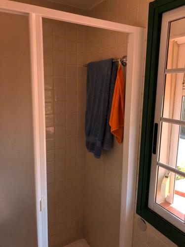 La salle de bains est pourvue d'une douche et de serviettes bleues et oranges. dans l'établissement APARTAMENTO EN LA LAGUNA, à La Laguna