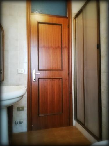 a wooden door in a bathroom with a sink at Colle dei lauri in Loreto
