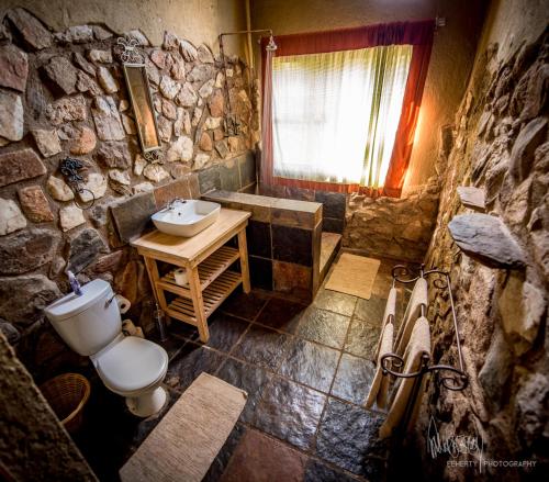 a stone bathroom with a toilet and a sink at Rio Dos Elefantes River Camp in Hoedspruit