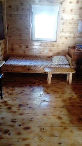 a bed in a wooden room with a window at Kuća Dragović Apartman in Kolašin
