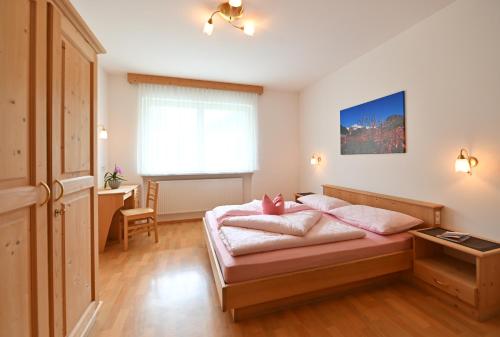 Un dormitorio con una cama con almohadas rosas. en Residence Obstgarten, en Coldrano
