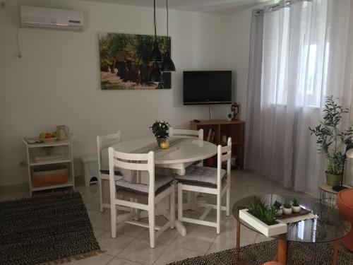 ein Wohnzimmer mit einem weißen Tisch und Stühlen in der Unterkunft Apartment Milin in Olib