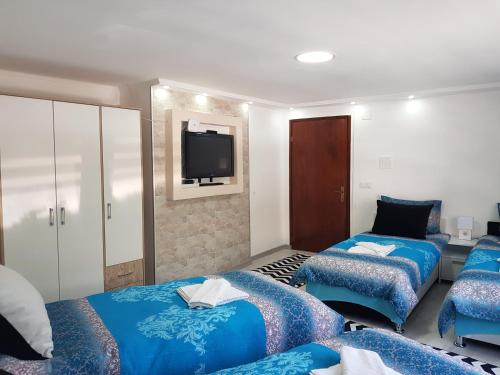 una habitación con dos camas y un televisor en la pared en ŠEHER Kuća, en Sarajevo
