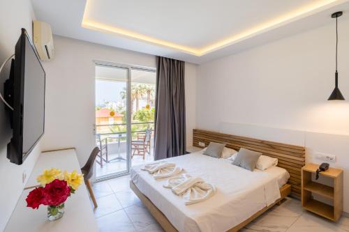 a hotel room with a bed and a balcony at Lardos Bay Hotel in Lardos