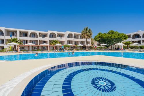 a swimming pool with a hotel in the background at Lardos Bay Hotel in Lardos