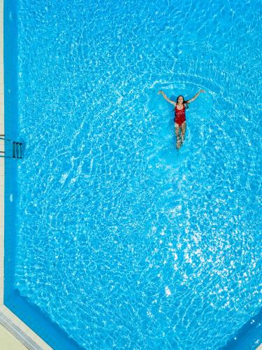 a woman swimming in a large pool of water at Lardos Bay Hotel in Lardos