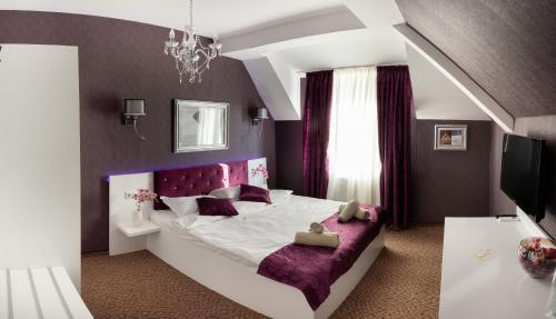 a bedroom with a large bed with a purple headboard at ANTIQUES & GOLD Boutique Guesthouse in Varna City