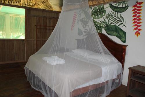 a bed in a room with a mosquito net at Topche, Centro Ecoturístico in Lacanjá