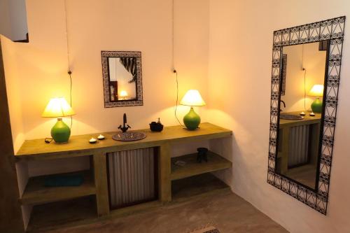 a room with a vanity with two lamps and a mirror at Casa Colonial Koenig in São Filipe