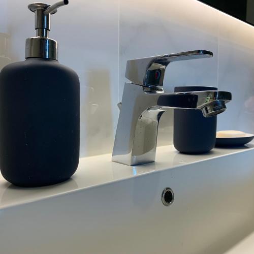 a soap bottle next to a faucet on a sink at De Amber Pattaya by ME in Bang Sare