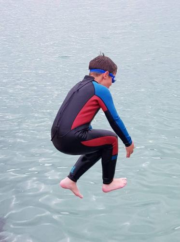 a boy in a wetsuit in the water at The butterbean accomodation in Carndonagh