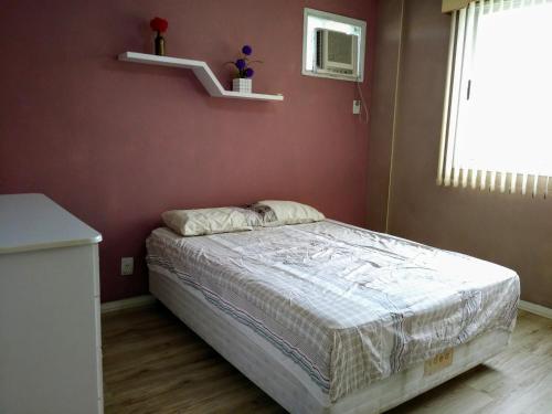 1 dormitorio con cama y pared roja en Apartamento Vila DR - Barra da Tijuca,prox Jeunesse,Arenas,Rio Centro,praias, Shopping, en Río de Janeiro