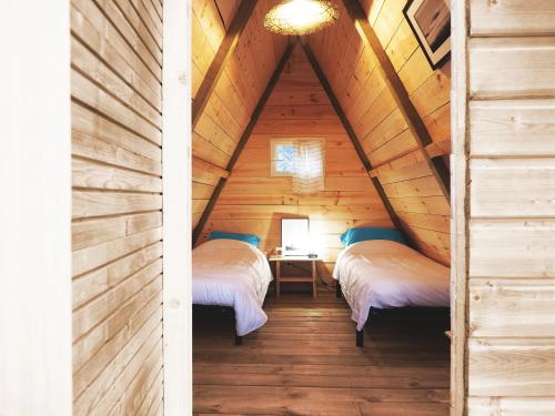 1 dormitorio con 2 camas en una cabaña de madera en Hoya Surf Camp - Activités + logements en Biscarrosse