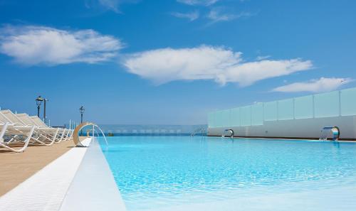 a swimming pool with chairs and a building at Marina di Petrolo Hotel & SPA in Castellammare del Golfo