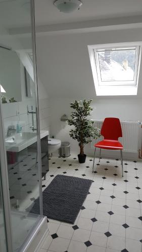 a bathroom with a red chair sitting on a tiled floor at Ferienhaus BARFLY in Traben-Trarbach